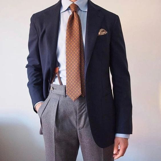 A navy Conxeppt blazer worn with grey trousers and a rust silk tie