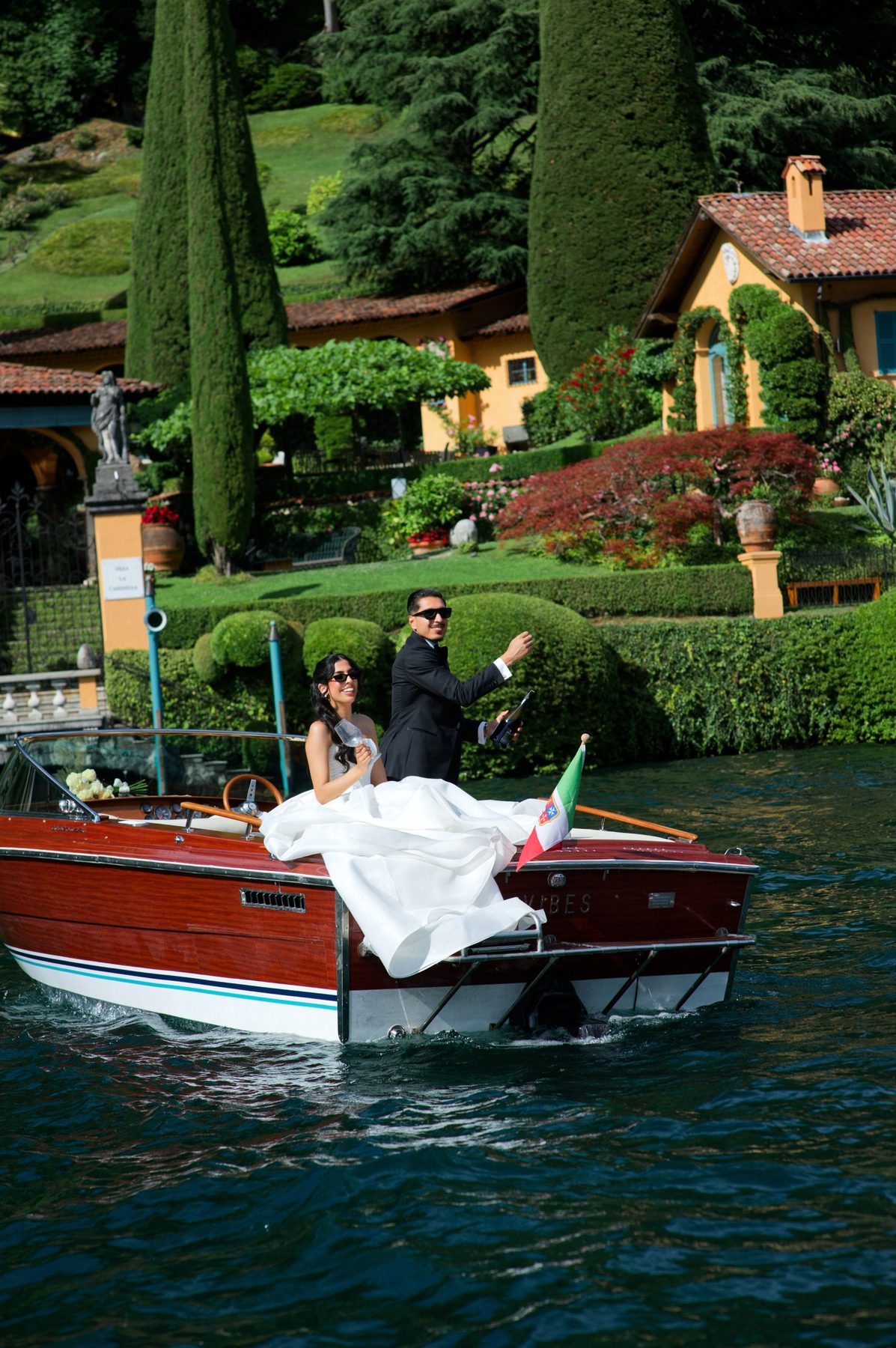 The bride boarding a wooden Riva, her gown across the deck
