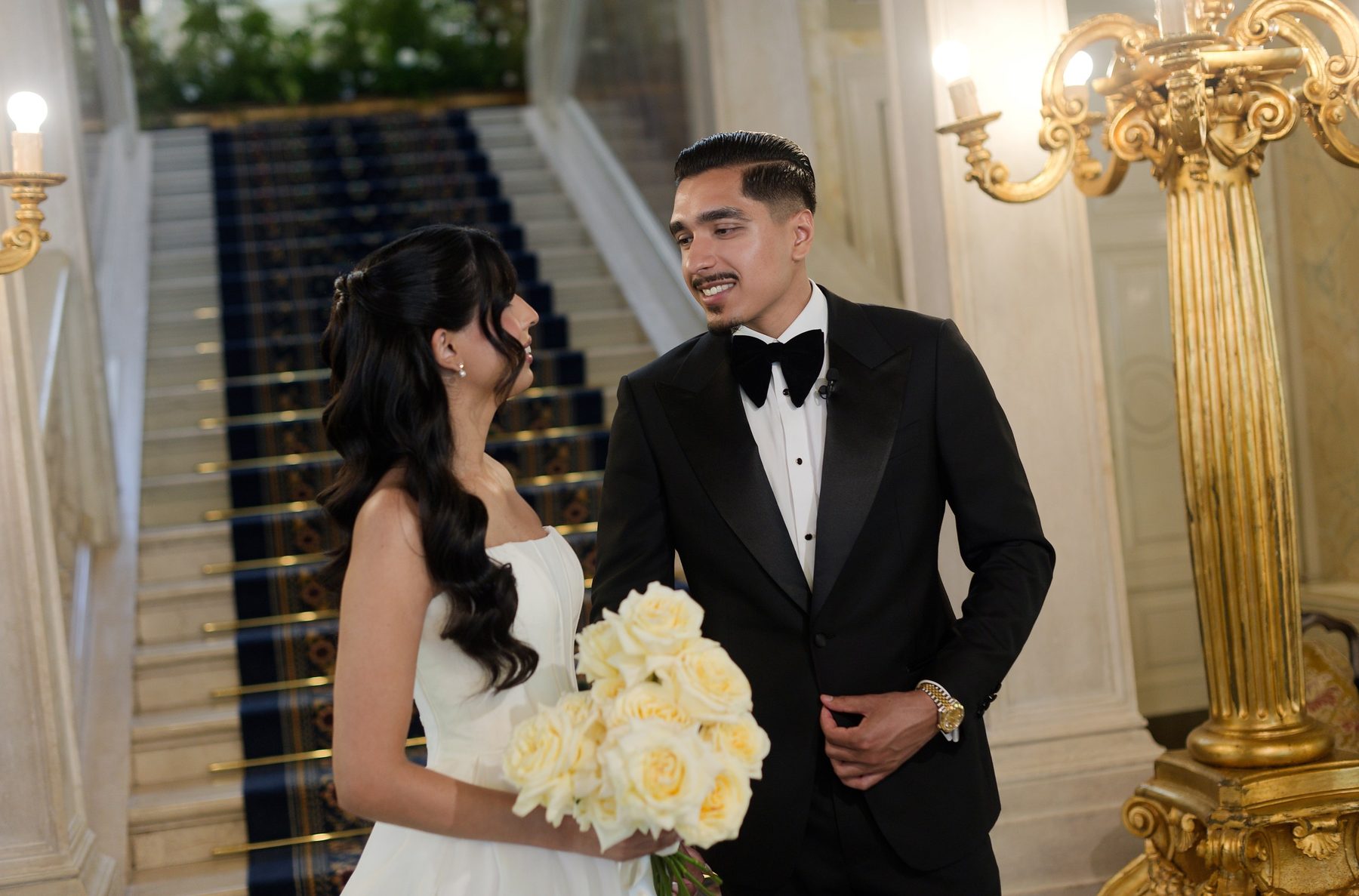 The couple on the villa stair, the bride holding a pale bouquet