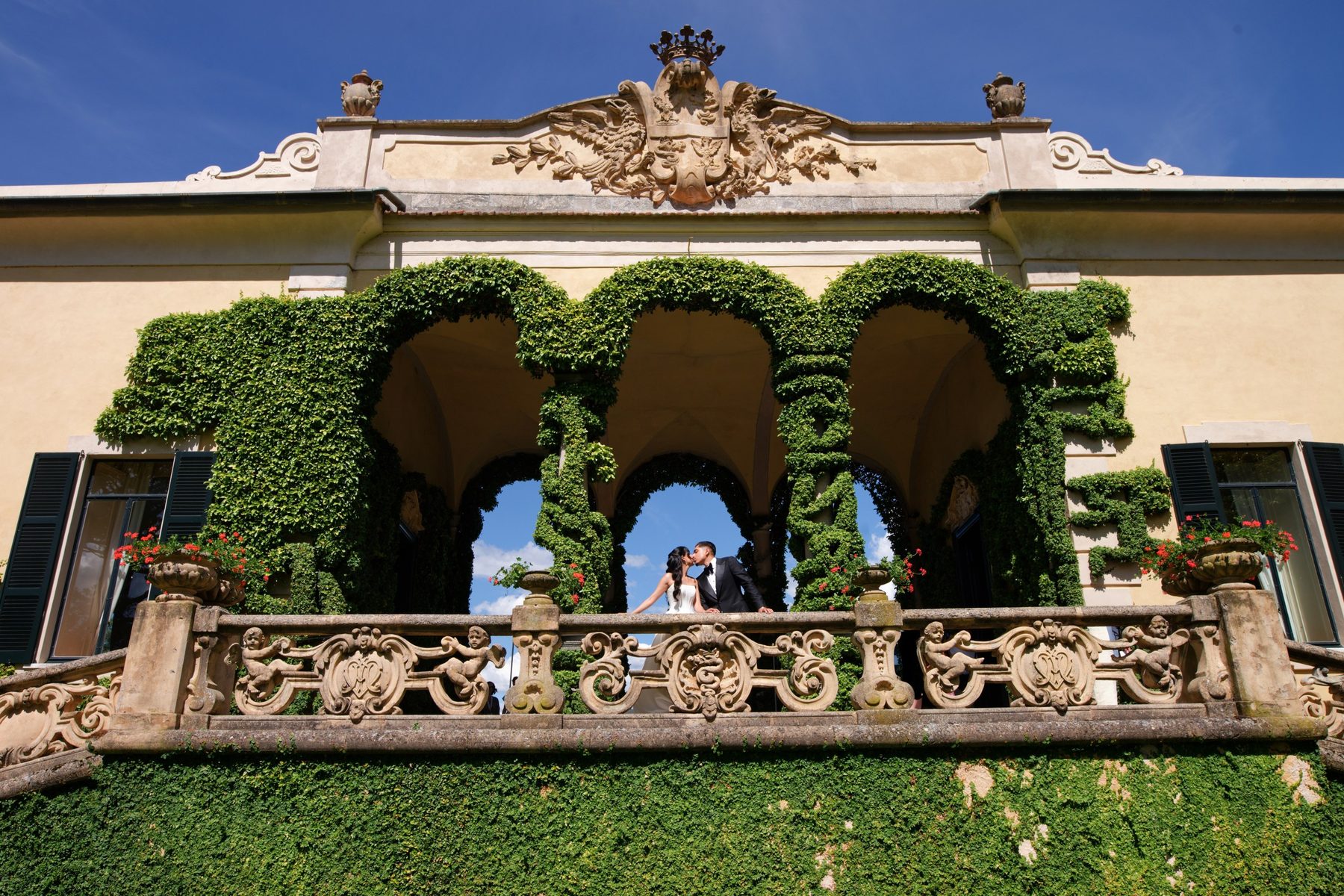 The couple framed by a stone arch in the villa garden