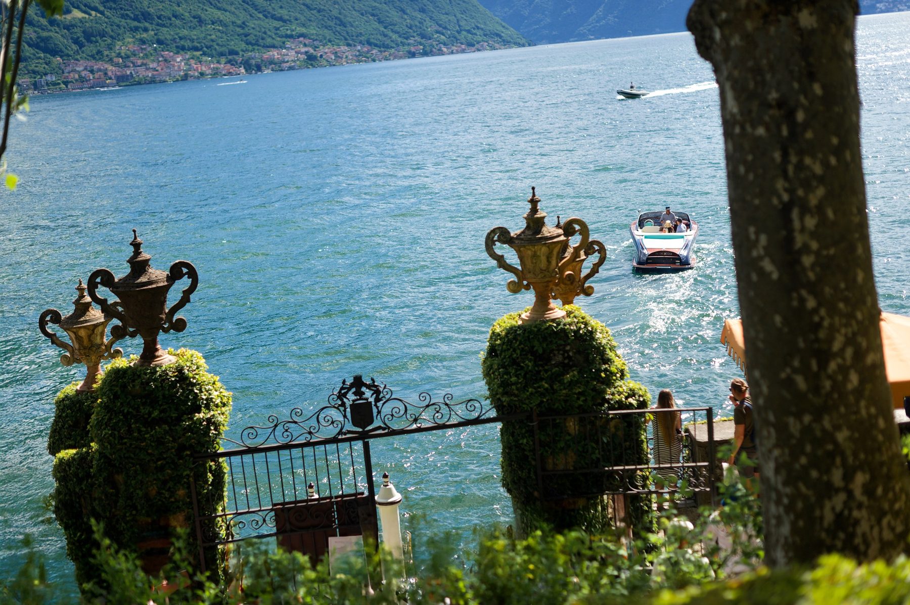 Stone urns on the villa terrace with the lake and boats beyond